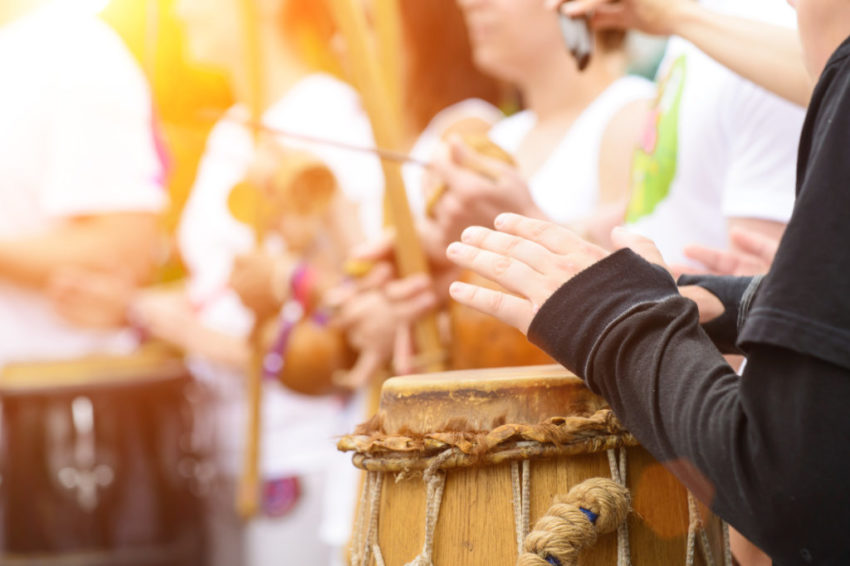 drummer with traditional Brazilian Drum and drum sticks in rays of the sun, selective focus